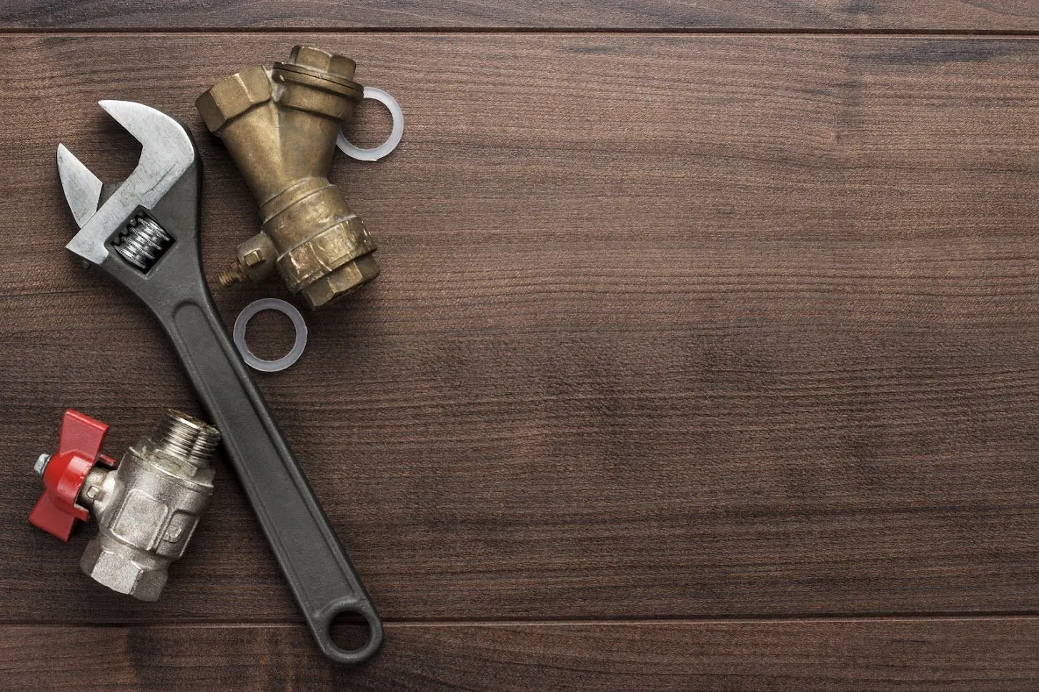 Pipe wrench, ball valve and "Y" pipe connecter rested on a wooden table