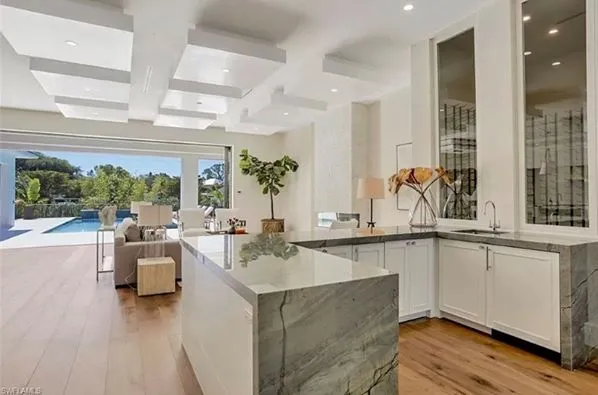 Finished kitchen in open floor plan with quartzite waterfall countertops and white cabinets