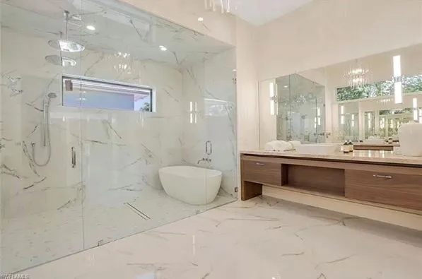 Finished bathroom with frameless shower glass, bathtub inside of shower, wood vanity with vessel sink