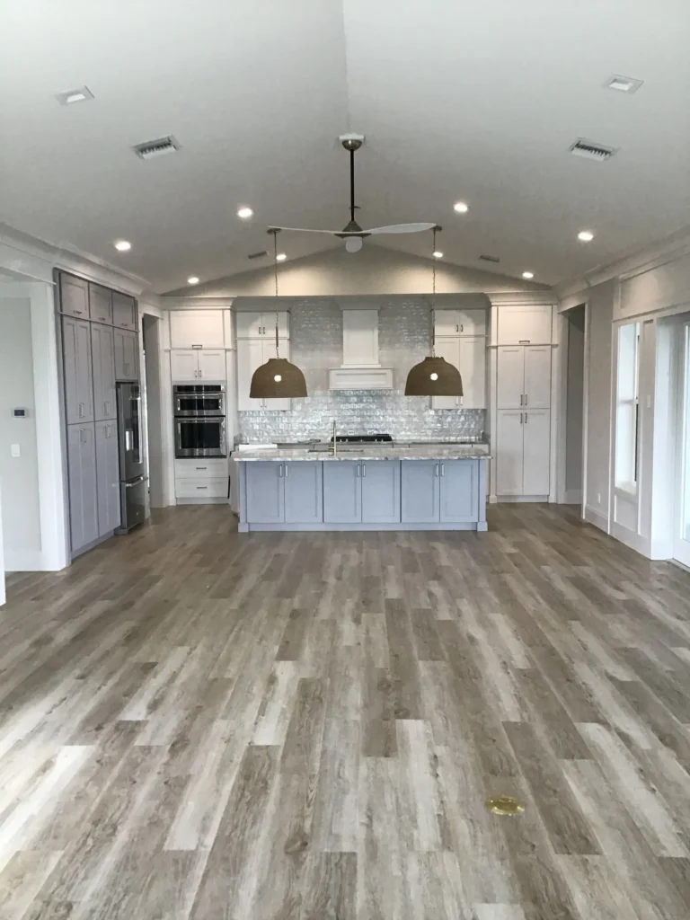 Head on picture of finished kitchen with cathedral ceiling, hardwood floors, granite island and two pendant lights over island