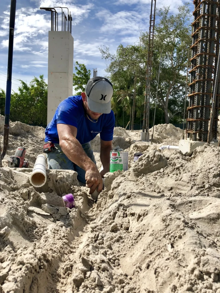 Plumber laying sewer line pipe on new construction site