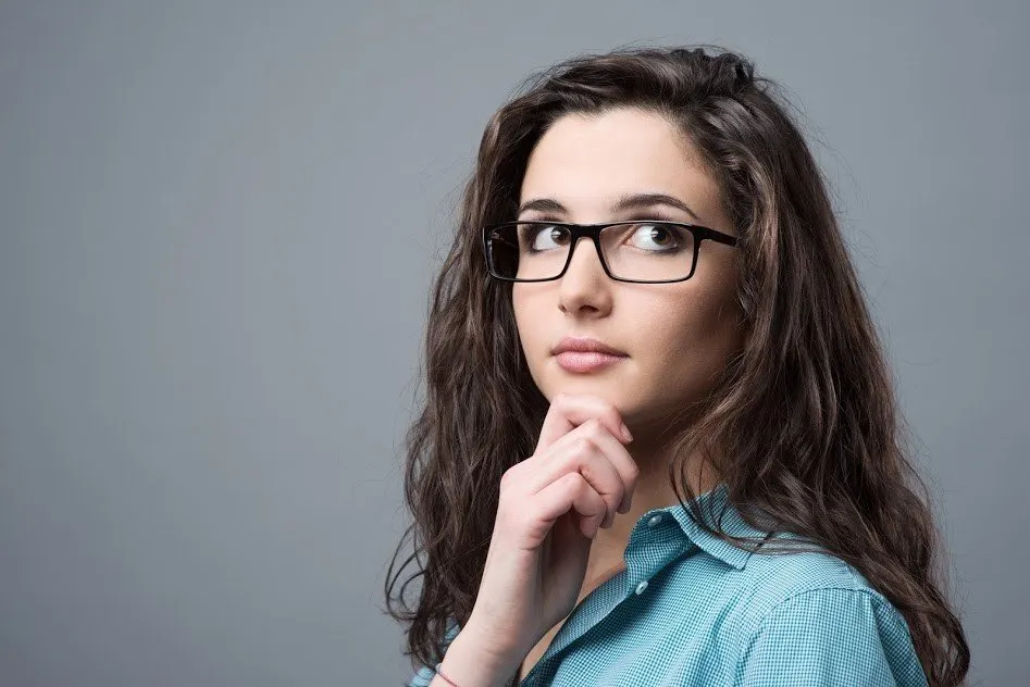 Curious woman with glasses on and her hand touching her chin