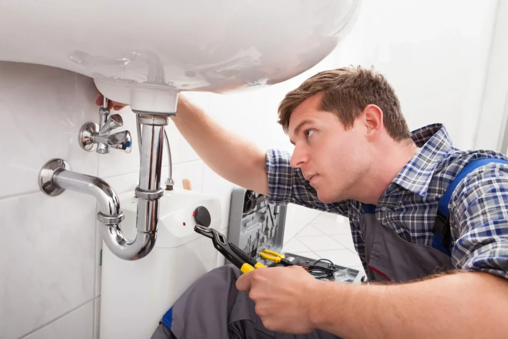 Plumber working on the drain of a commercial bathroom sink