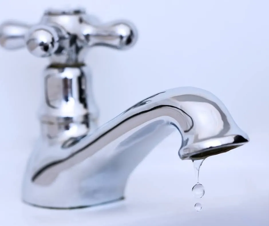 Close up picture of a leaking chrome bathroom faucet