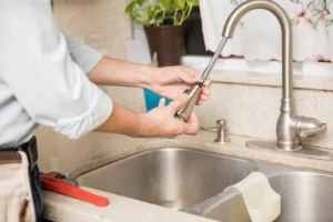 Plumber pulling the extension spray hose out of a kitchen faucet